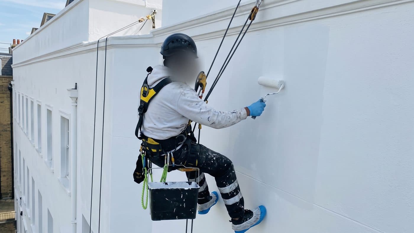 Illustration of a rope access technician painting a white parapet elevation