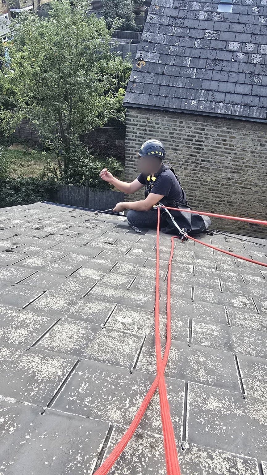 Rope lines rigged across the slate pitch to reach the chimney stack