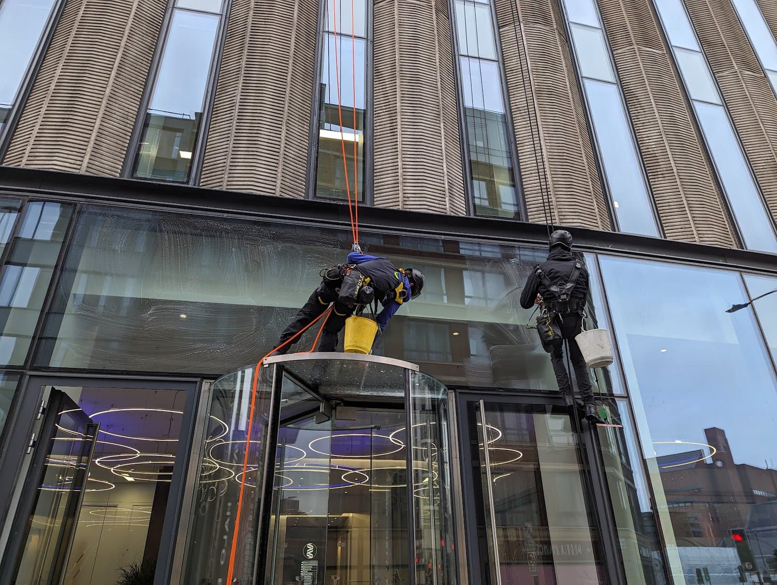 Two technicians finishing the glazing above the building entrance