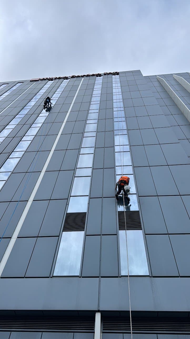 Two rope access technicians cleaning the hotel tower elevation below the parapet signage