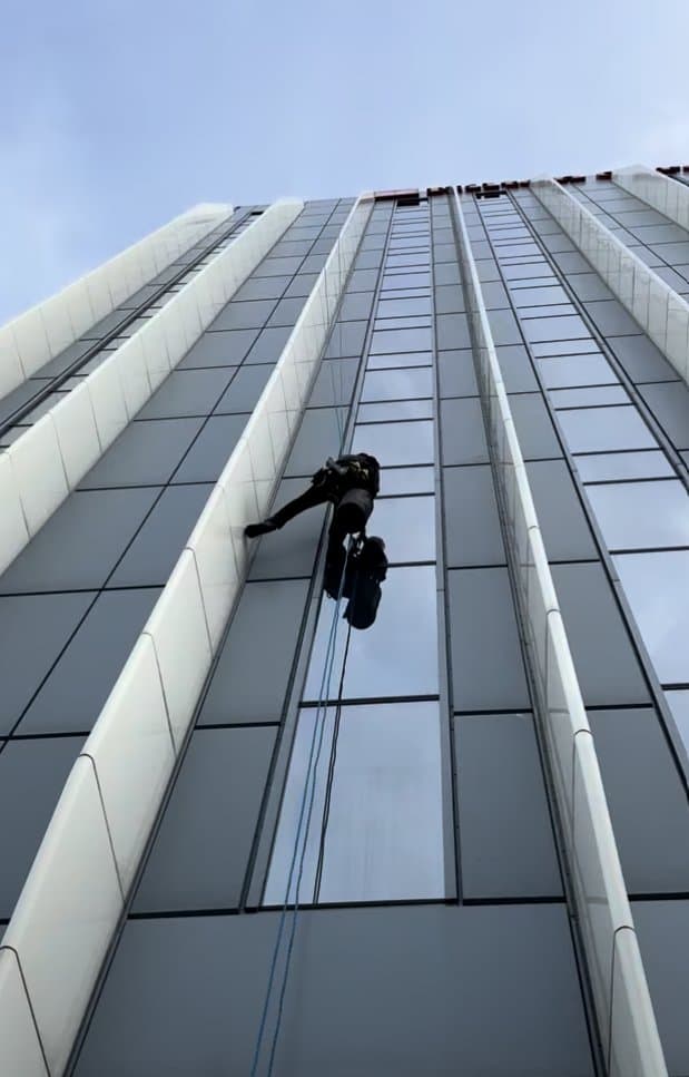 Technician descending the corner return between the vertical fins and glazing