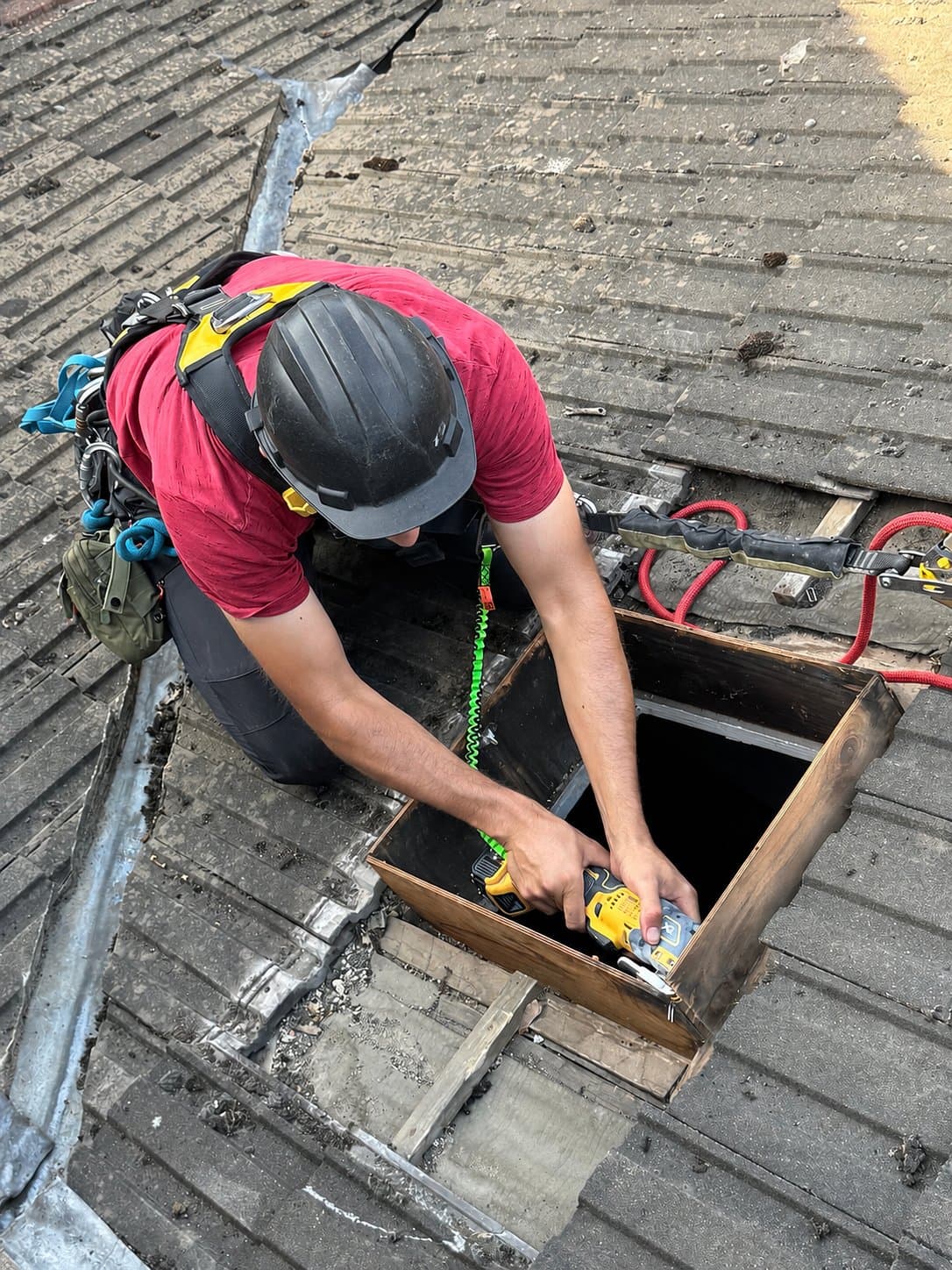 Rope access technician drilling the rooflight kerb, drill tethered to the harness