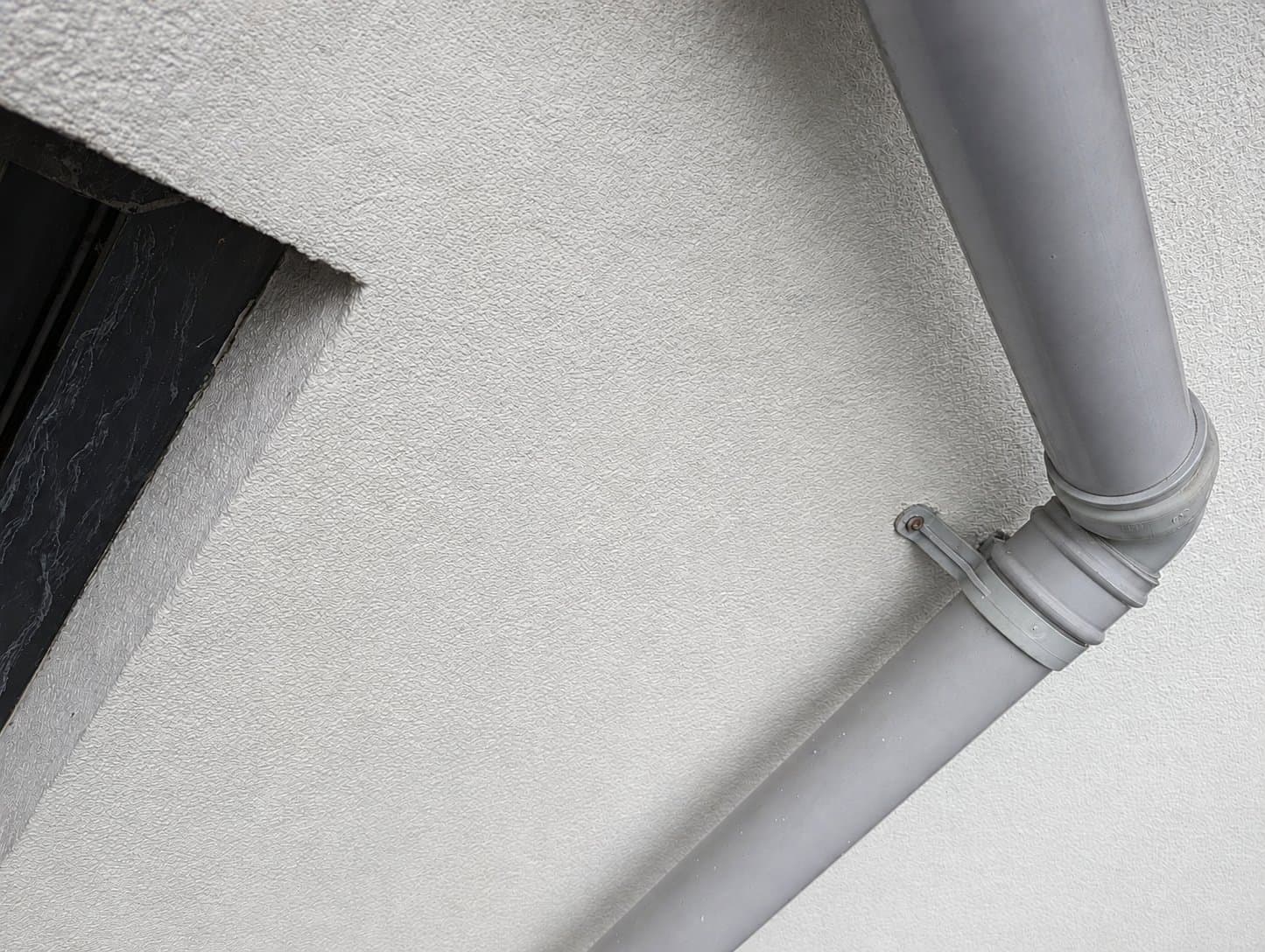 After: the same corner with new render, fresh paint and a clear downpipe